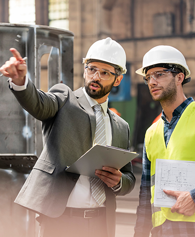 Manager and steel worker talking and looking away in factory